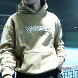 Person wearing a beige hoodie with a logo on a sports court